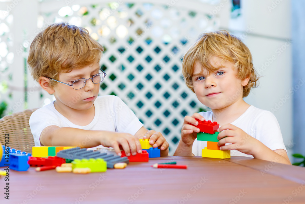 Two little kid boys playing with plastic blocks together Two little kid boys playing with plastic blocks together