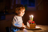 Little kid boy celebrating his birthday and blowing candles on cake