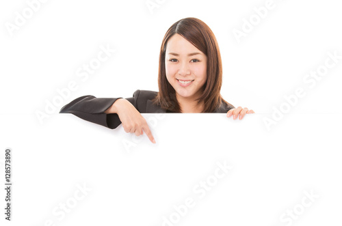 Smiling business woman pointing on billboard over white background