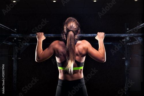 Strong girl in sportswear doing pull up exercise