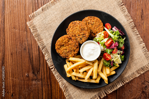 Serving of falafel and chips served on a black plate with sauce.