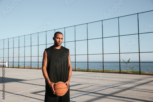 Portrait of a young basketball player standing at the playgroung photo