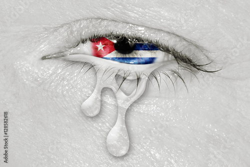 Crying eye with Cuba Flag iris on black and white face. concept of sadness for Cuba, patriotic metaphor.