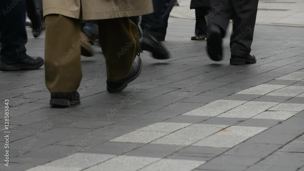 Unidentifiable people step across a road by crosswalk or zebra crossing. Pedestrian crossing in a city. Unidentifiable people step across a road by crosswalk or zebra crossing. Pedestrian crossing in a city.