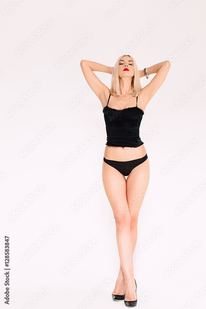 Beautiful sexy woman in black lingerie, in underwear with tan skin and red lips posing in studio on white background. Contrasting retouched shot