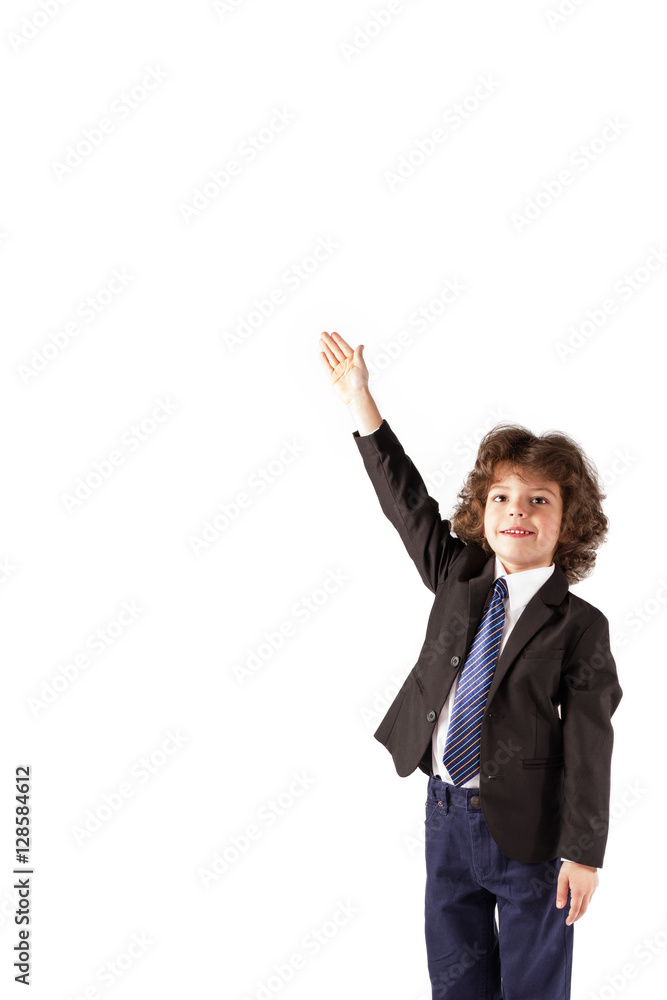 Funny curly-haired boy raised his hand in a business suit, smiling and looking at the camera. White background. Funny curly-haired boy raised his hand in a business suit, smiling and looking at the camera. White background.