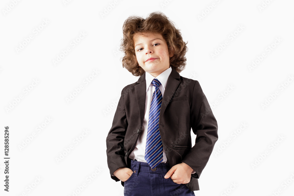 Curly trendy boy in a business suit standing and looking at the camera, his head thrown back. Hands holding in their pockets. White background. Curly trendy boy in a business suit standing and looking at the camera, his head thrown back. Hands holding in their pockets. White background.