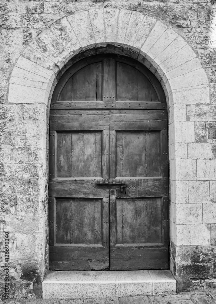 The entrance wooden door in an old Italian house. (black and white). The entrance wooden door in an old Italian house. (black and white).