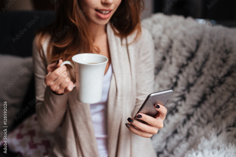 Smiling happy woman holding mobile phone and cup of tea Smiling happy woman holding mobile phone and cup of tea