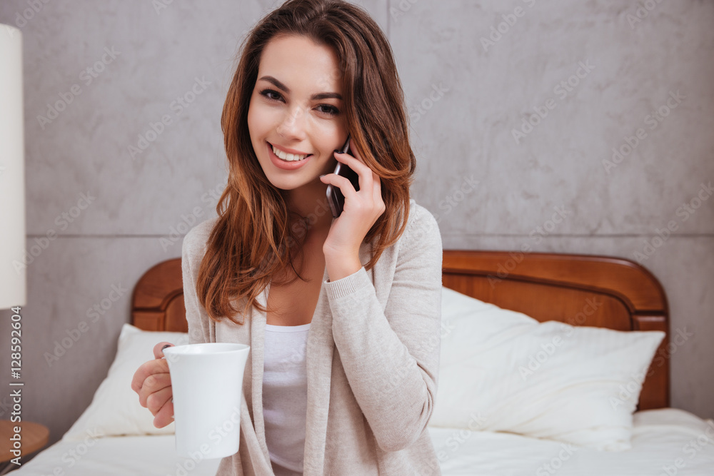 Woman talking on mobile phone and drinking cup of tea Woman talking on mobile phone and drinking cup of tea