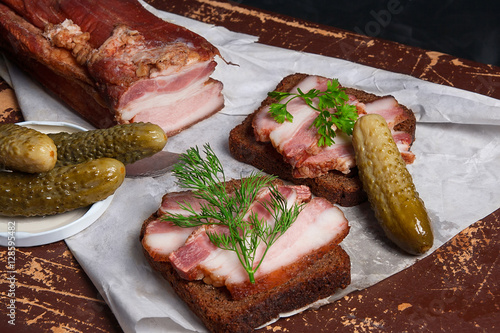 Smoked bacon with rye black bread and several pickles on the pac photo