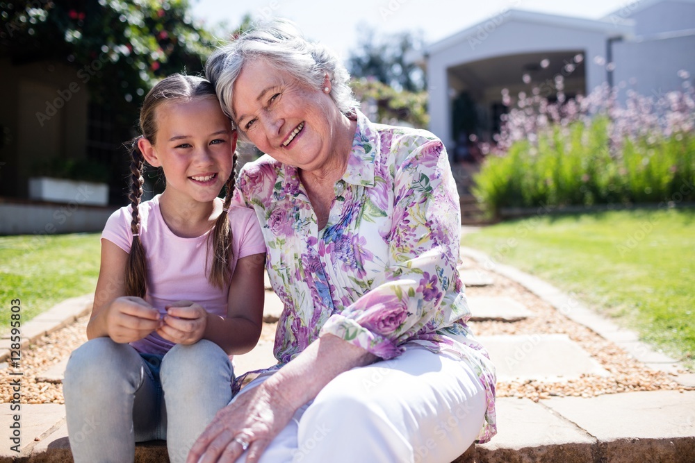 Fototapeta premium Grandmother and granddaughter sitting in the garden