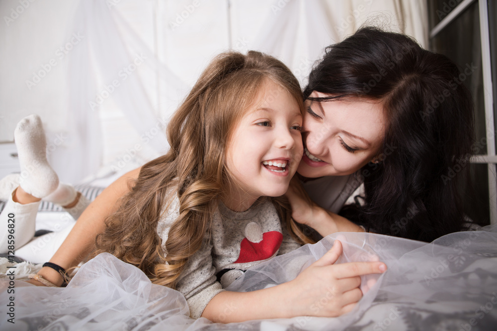 Happy loving family. Mother and daughter playing and hugging on a bed
Happy loving family. Mother and daughter playing and hugging on a bed