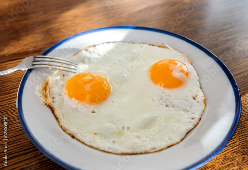 Fried eggs like a smily face on the tray with the light blue platter