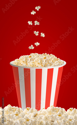 Popcorn in classic striped bucket on red background