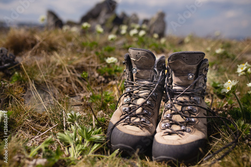 Trekking heavy boots with flowers in bloom and green grass ar spring