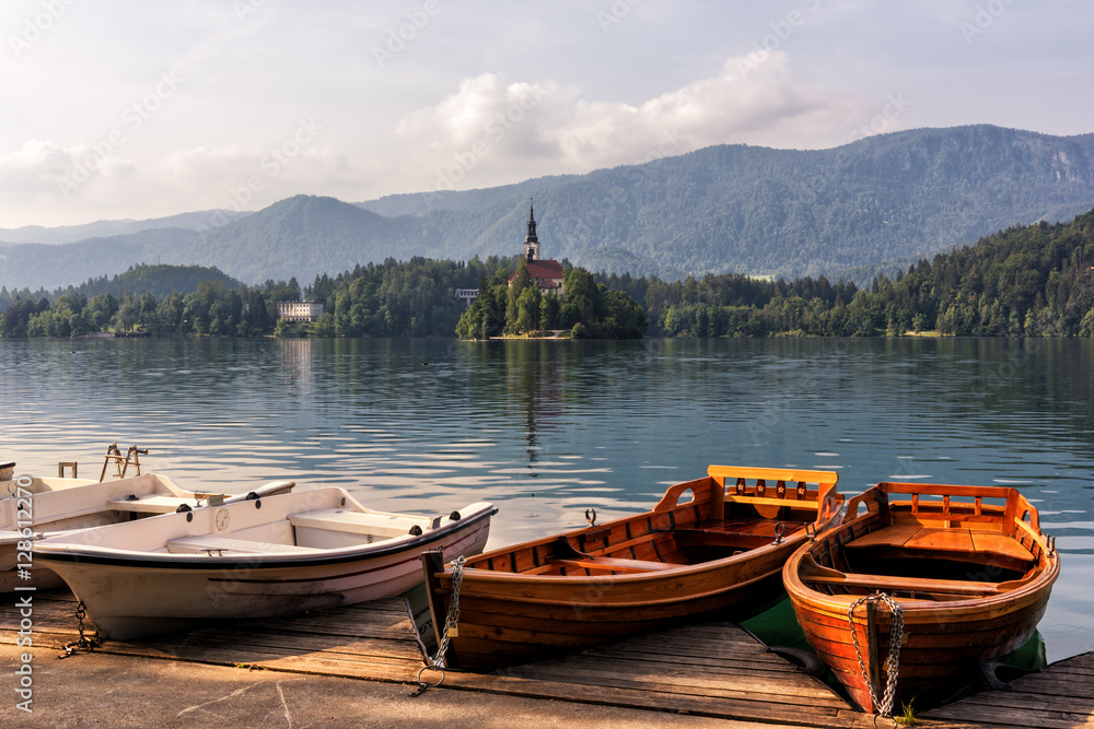 Wooden pier with pleasure boats on the alpine lake Bled and Alps mountains background, Slovenia, Europe