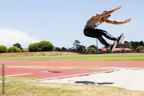 Athlete performing a long jump photo