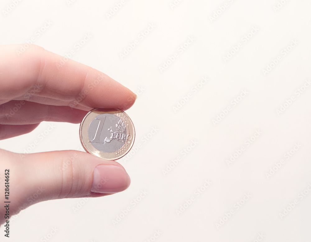 Woman's hand holding a coin one euro on white background. Business concept Woman's hand holding a coin one euro on white background. Business concept