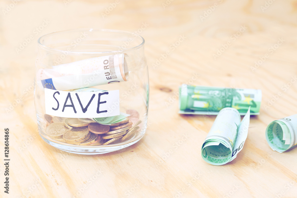 Savings money box coins with stick note paper on wooden background. Euro bank note. Jar for savings full of euro. Savings money box coins with stick note paper on wooden background. Euro bank note. Jar for savings full of euro.