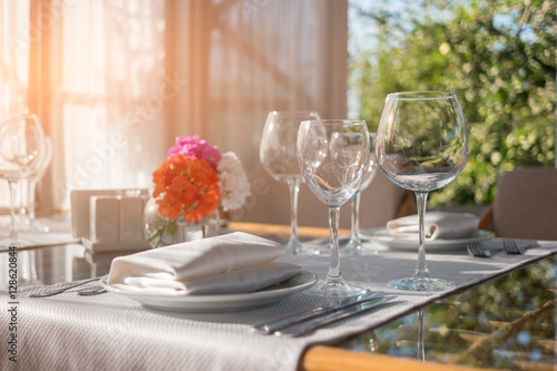 Plates and glasses on table. Dining table and sunshine. Invite neighbours for lunch. Create the perfect cleanliness.