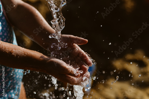 Child hand and water wet sand blurry outdoors background