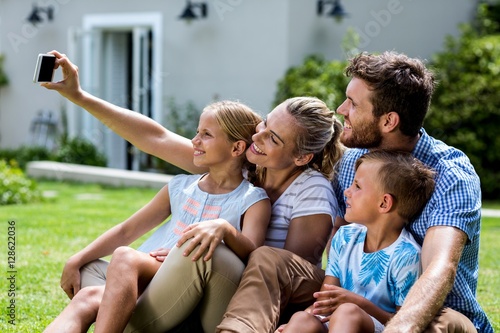 Happy mother taking selfie with family in yard 