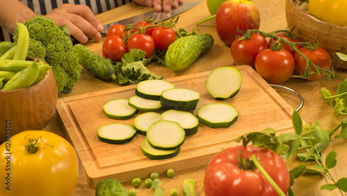 Zucchini slices on wood board on table with vegetables