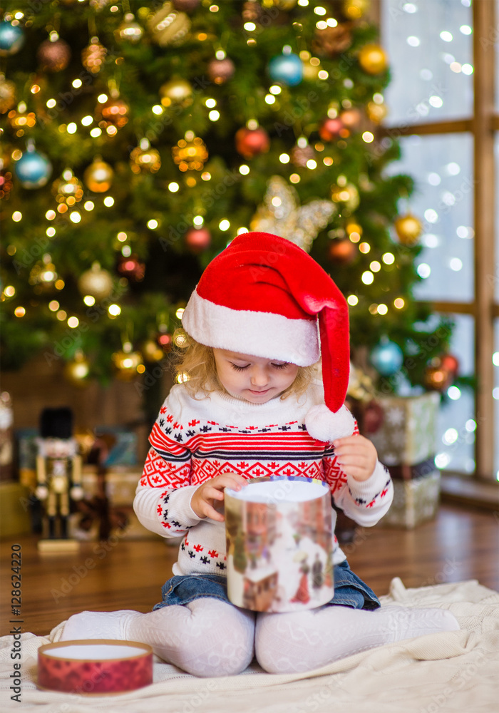 Young girl in red santa hat opening Christmas gifts Young girl in red santa hat opening Christmas gifts