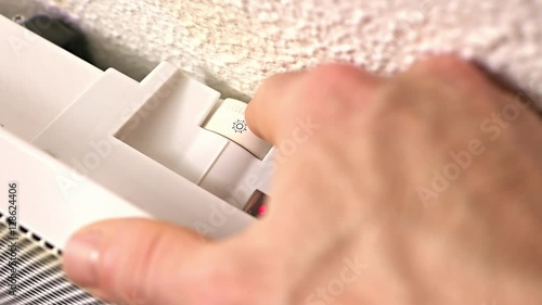 détail main d’homme qui allumme un radiateur électrique
