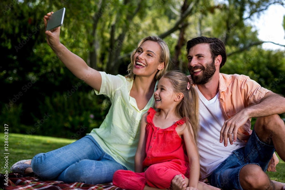 Woman taking selfie with husband and daughter at yard 