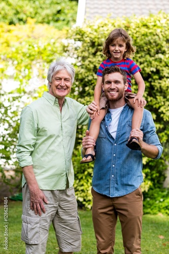 Grandfather standing with son carrying grandson at yard 