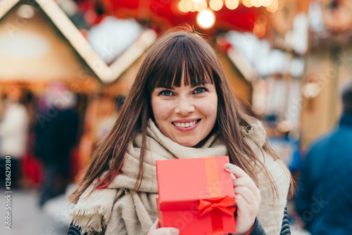 beautiful woman holding a present box on a christmas market