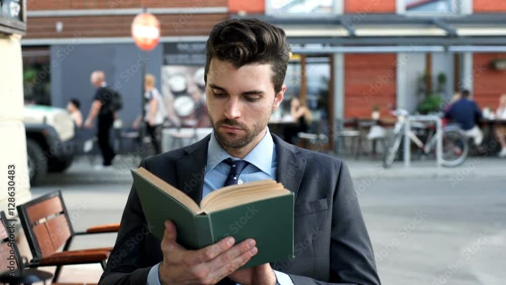 Businessman looking absorbed while reading book in the outdoor cafe, steadycam shot
Businessman looking absorbed while reading book in the outdoor cafe, steadycam shot