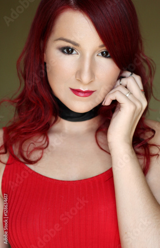 The young redhead woman in red top with black ribbon on the neck