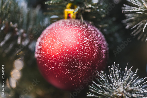 Beautiful New Year decorations, red shimmering ball in snow clos