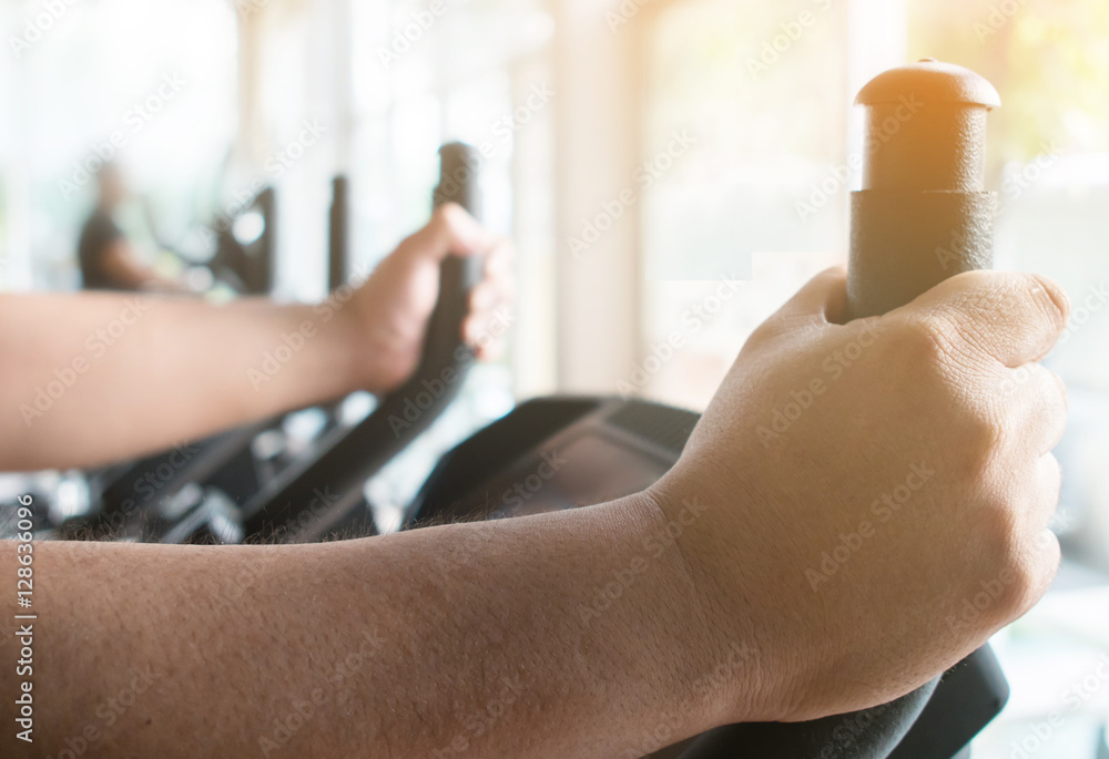 Close up fat man hands on exercise bike.