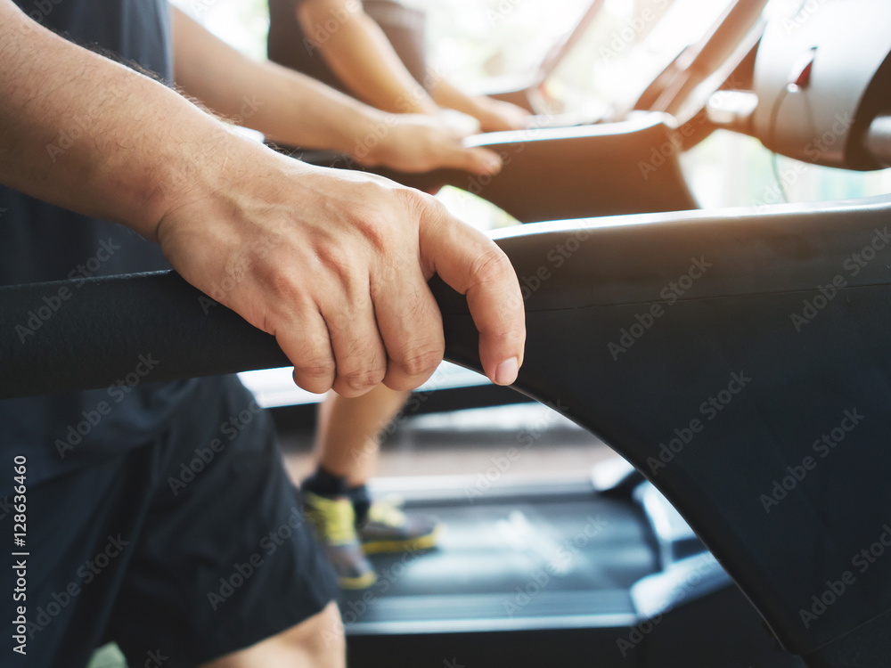 Obraz premium man hands holding on treadmill machine while working out at a gy
