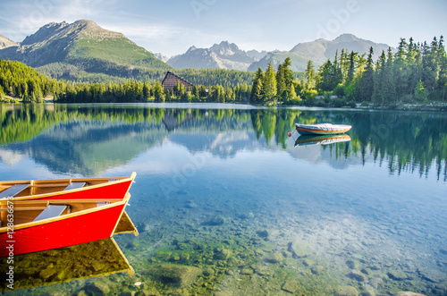 Lake Strbske Pleso with colorful red boats and big mountain on the background in Slovakia. Original wallpaper from summer morning