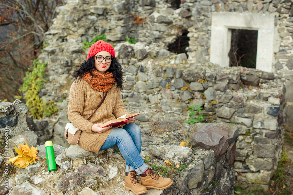 Fototapeta premium Beautiful girl read book near old castle. Autumn time.