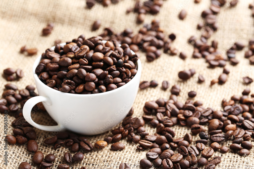 Brown roasted coffee beans in cup on sackcloth Brown roasted coffee beans in cup on sackcloth