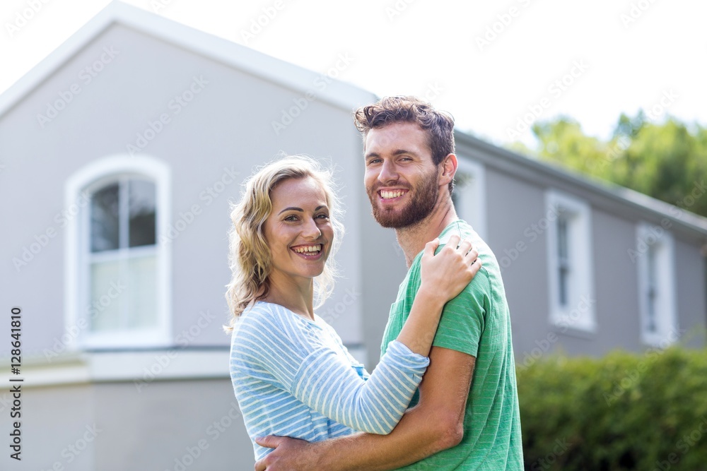 Naklejka premium Couple embracing against house