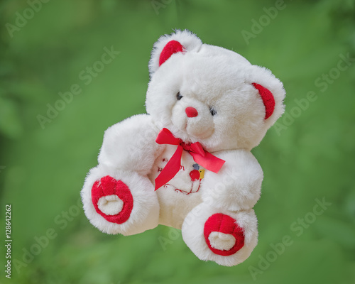 Fototapeta Naklejka Na Ścianę i Meble -  White toy teddy bear on a green background .