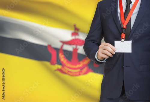 Businessman holding name card badge on a lanyard with a national flag on background - Brunei