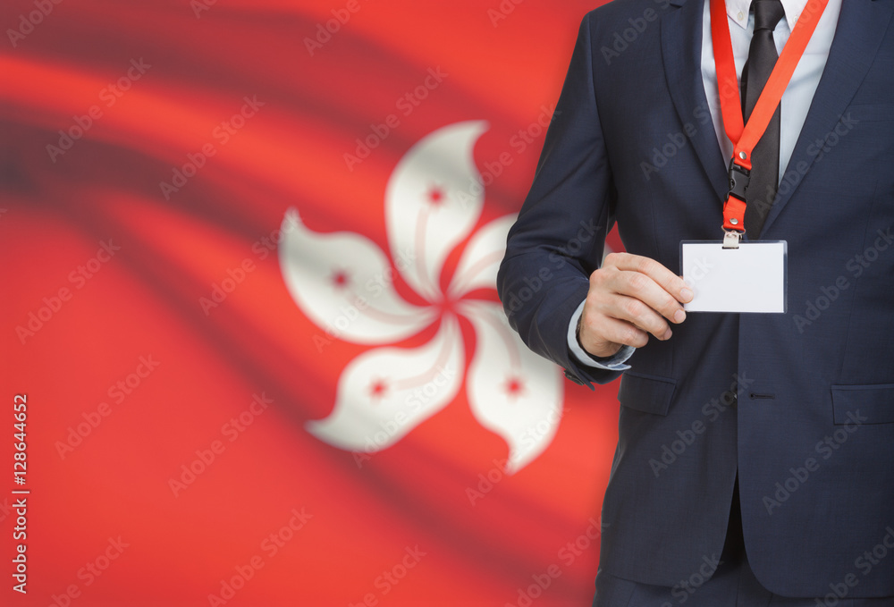Businessman holding name card badge on a lanyard with a national flag on background - Hong Kong