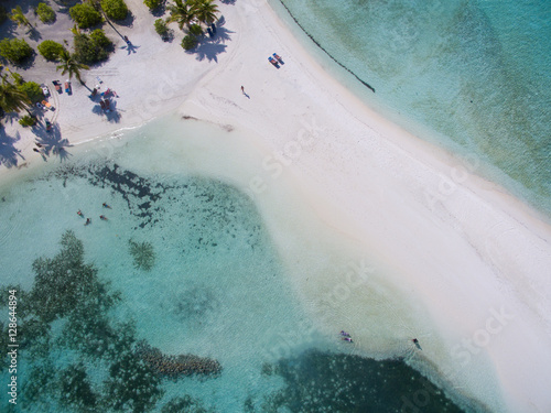 Landscape seascape aerial view over a Maldives Male Atoll island. White sandy beach and tiny people seen from above.