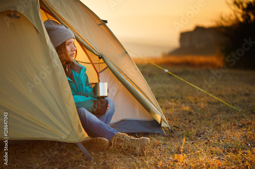 Young woman in sports wear and trekking shoes sitting in bivouac
