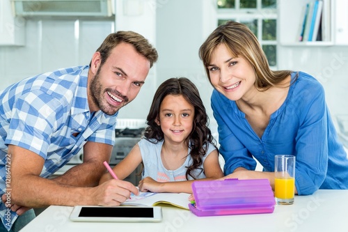 Happy father and mother assisting daughter in homework at home