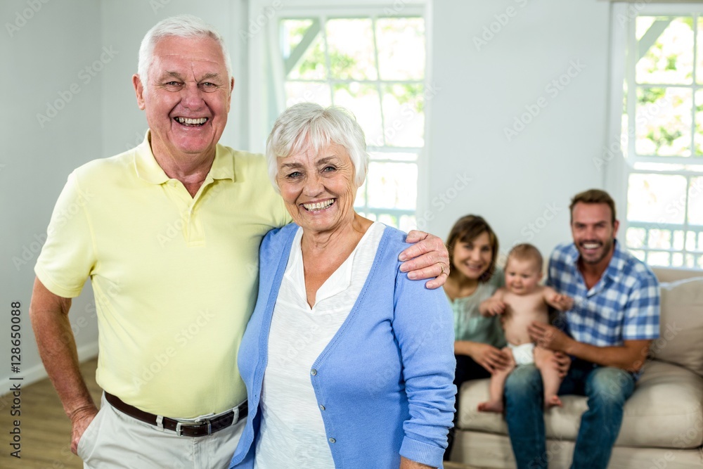 Happy senior couple with family sitting in background Happy senior couple with family sitting in background