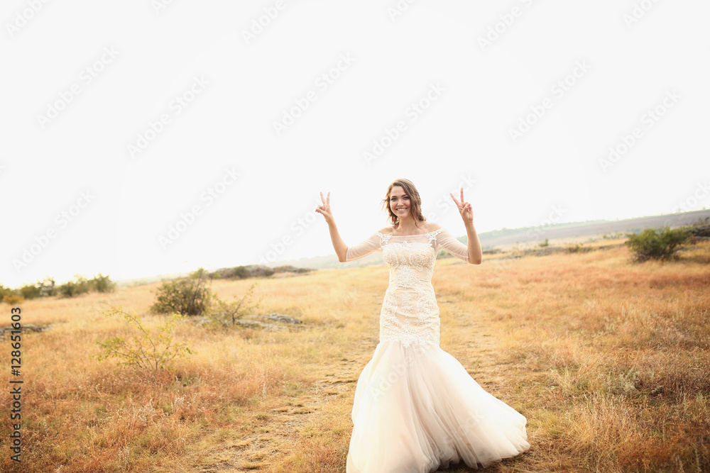 beautiful bride in a white dress stands outdoors